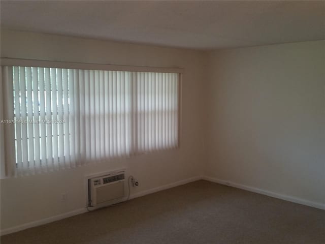 carpeted spare room featuring a wall mounted air conditioner