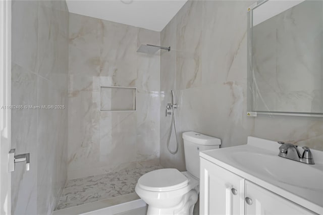 bathroom with toilet, a tile shower, and vanity