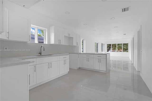 kitchen featuring sink, backsplash, and white cabinets