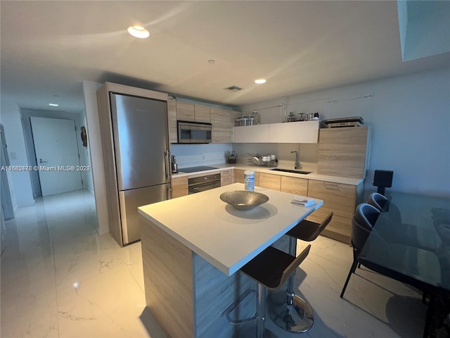 kitchen with a kitchen island, a kitchen breakfast bar, light brown cabinetry, black appliances, and sink