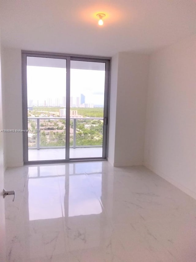 empty room with a city view, a wall of windows, a healthy amount of sunlight, and marble finish floor