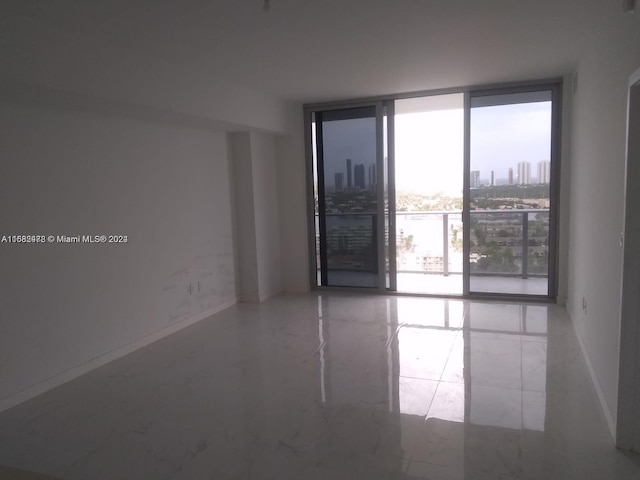 spare room with expansive windows, a view of city, and baseboards