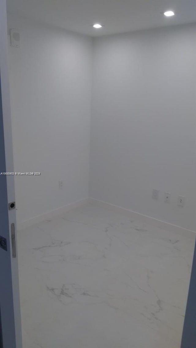 unfurnished room featuring baseboards, recessed lighting, and marble finish floor