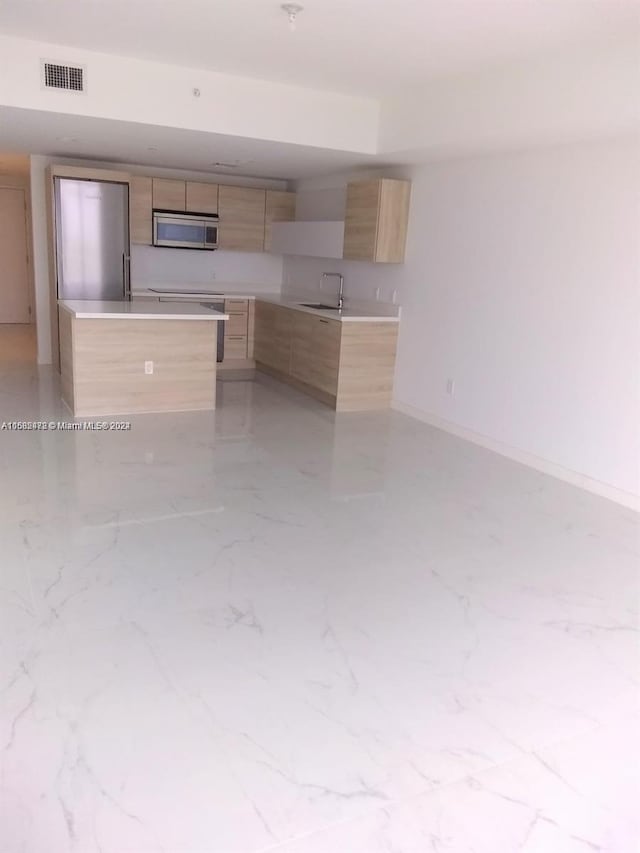 kitchen featuring visible vents, modern cabinets, stainless steel microwave, marble finish floor, and light brown cabinets