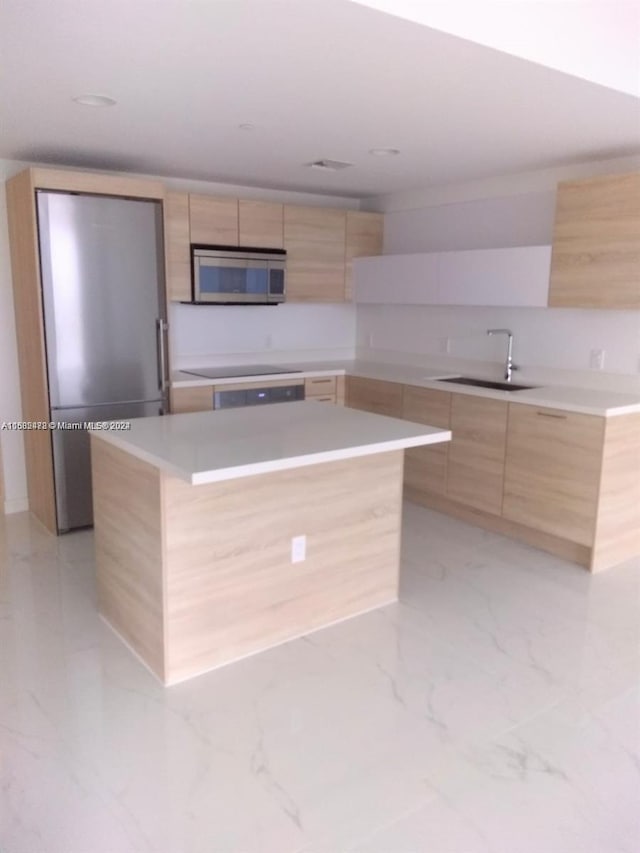 kitchen featuring light brown cabinets, black electric cooktop, a center island, and sink