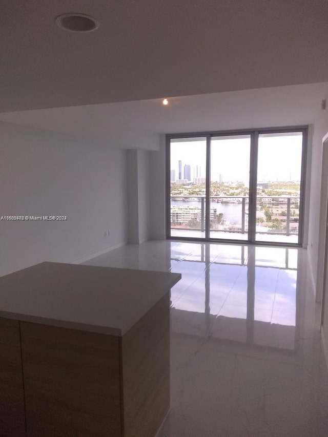 unfurnished room with a healthy amount of sunlight, a water view, light tile patterned floors, and a city view