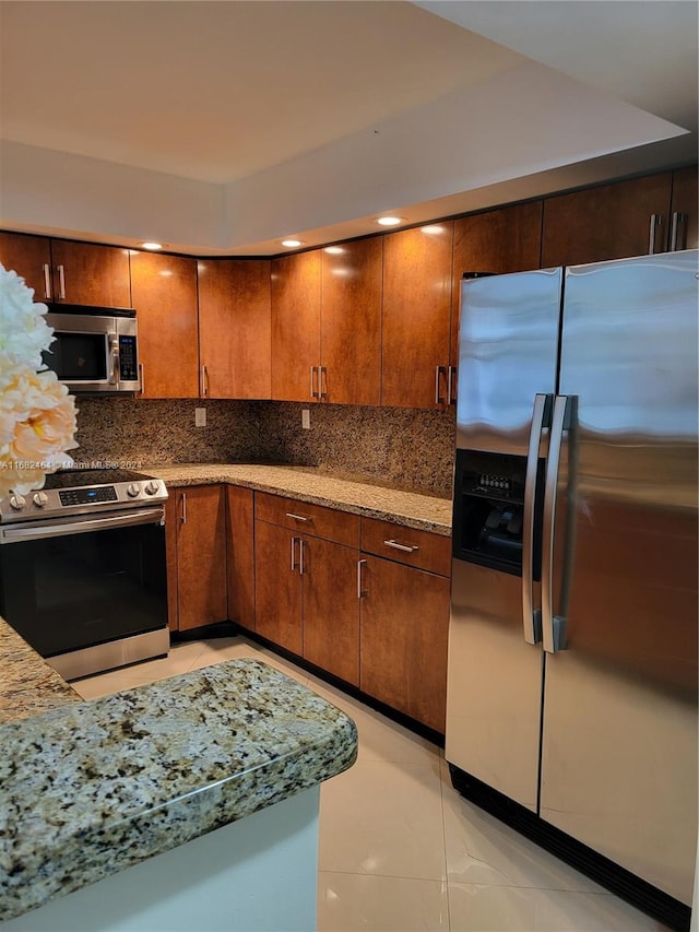 kitchen with light tile patterned flooring, tasteful backsplash, stainless steel appliances, and light stone countertops