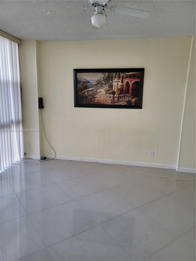 tiled empty room with a textured ceiling and ceiling fan