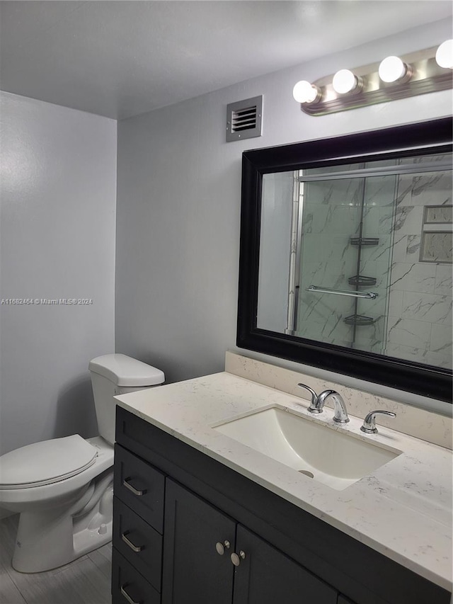 bathroom with vanity, toilet, and a shower with shower door