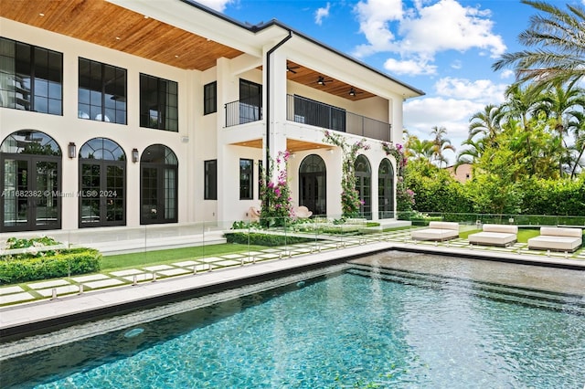 rear view of house featuring a patio, a fenced in pool, and a balcony