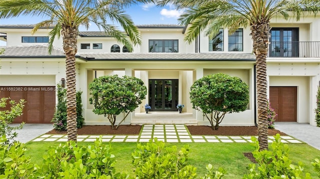 view of front of property with a balcony, a front yard, and a garage