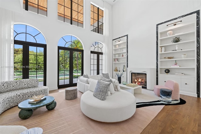 living room featuring french doors, hardwood / wood-style flooring, a high ceiling, and built in shelves