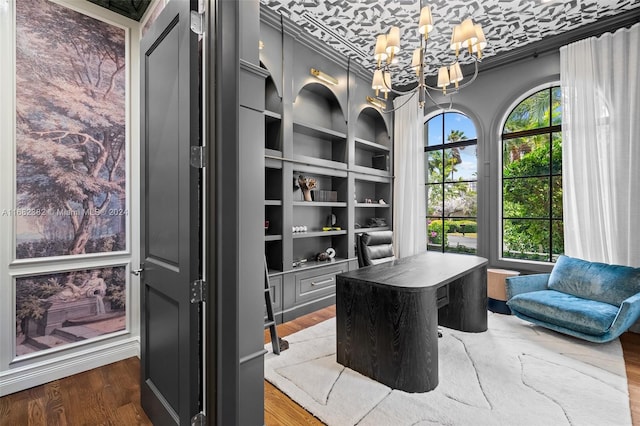 office area with built in shelves, crown molding, hardwood / wood-style flooring, and an inviting chandelier