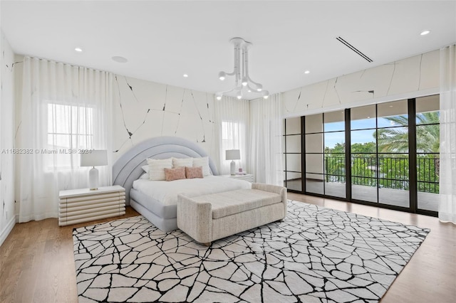 bedroom with hardwood / wood-style flooring, access to outside, and an inviting chandelier