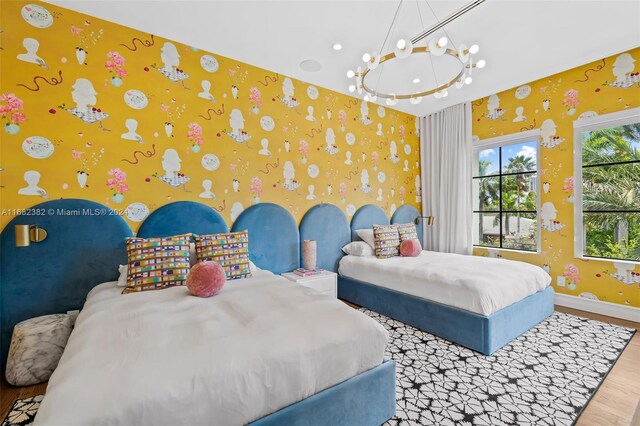 406 Tamarind Dr, Hallandale Beach, FL 33009 - bedroom featuring wood finished floors, wallpapered walls, baseboards, and a chandelier