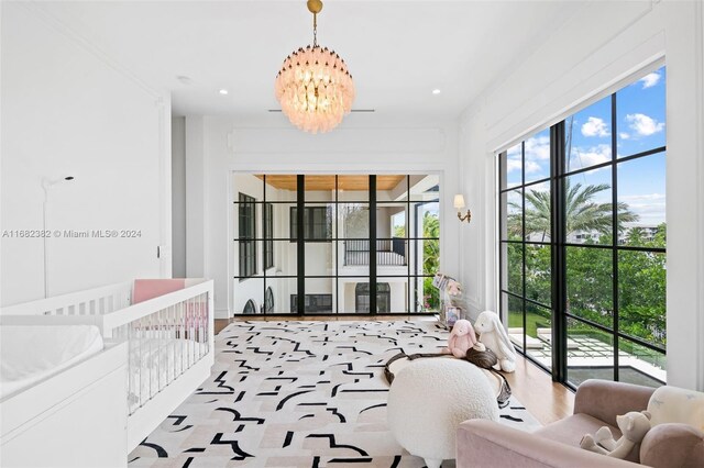 bedroom featuring a nursery area and an inviting chandelier