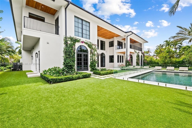 back of property with a fenced in pool, a patio area, a lawn, and a balcony