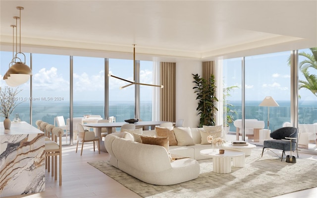 living room with floor to ceiling windows, a water view, and light wood-type flooring