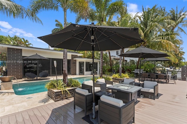 wooden deck featuring a fire pit and pool water feature