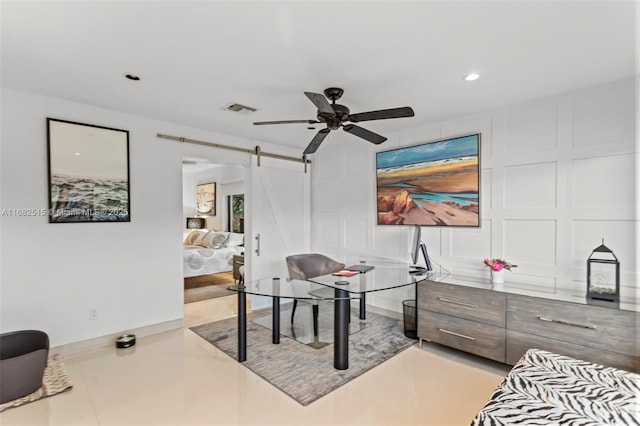 office space featuring a barn door and ceiling fan