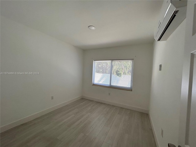 spare room with a wall mounted air conditioner and light wood-type flooring