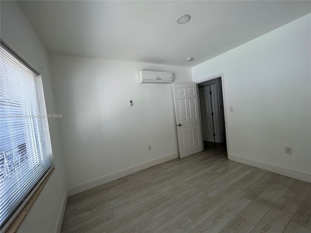 spare room featuring a wall mounted air conditioner and light wood-type flooring