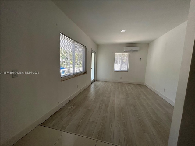 spare room with light wood-type flooring and a wall unit AC