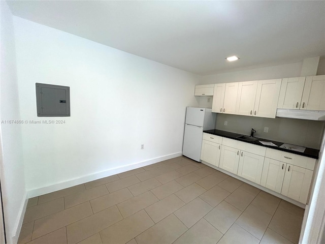 kitchen featuring white fridge, light tile patterned floors, electric panel, and white cabinets