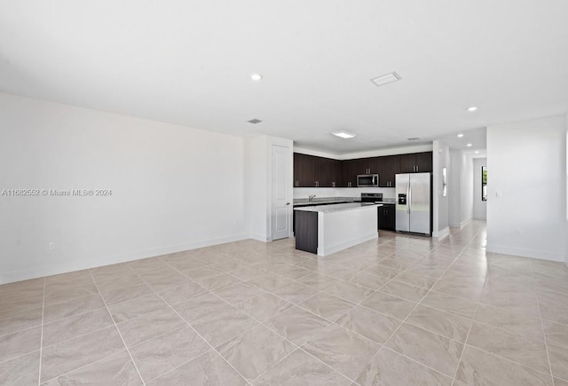 kitchen featuring a kitchen island, dark brown cabinets, stainless steel appliances, and light tile patterned floors