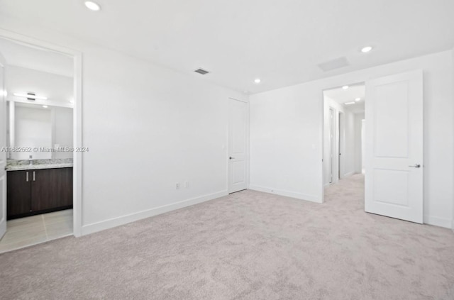 unfurnished bedroom featuring light colored carpet and connected bathroom