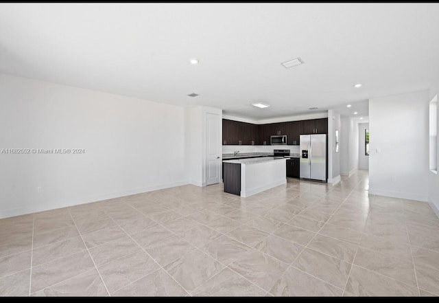 kitchen featuring a kitchen island, stainless steel appliances, sink, dark brown cabinetry, and light tile patterned floors