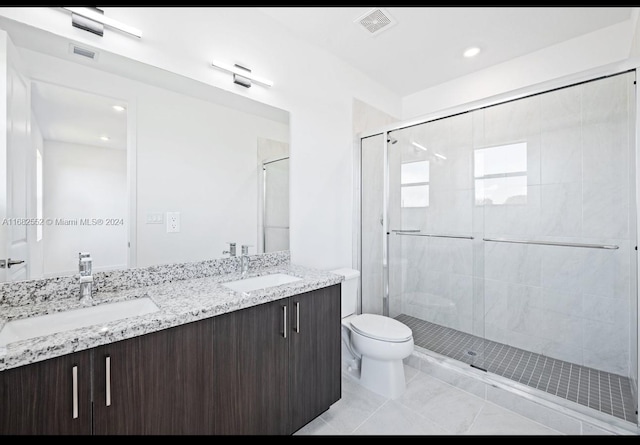 bathroom with vanity, toilet, a shower with shower door, and tile patterned flooring