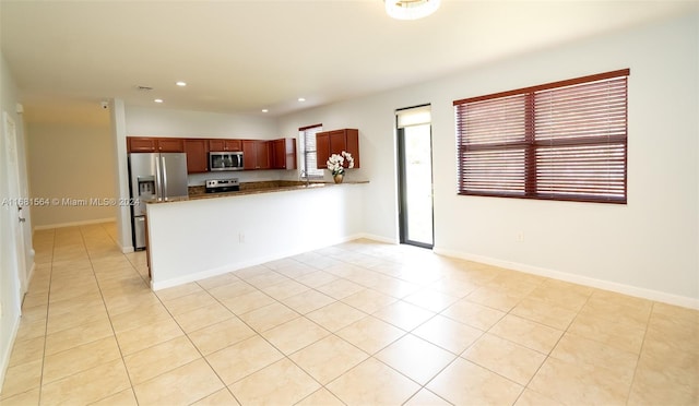 kitchen with appliances with stainless steel finishes, kitchen peninsula, and light tile patterned floors