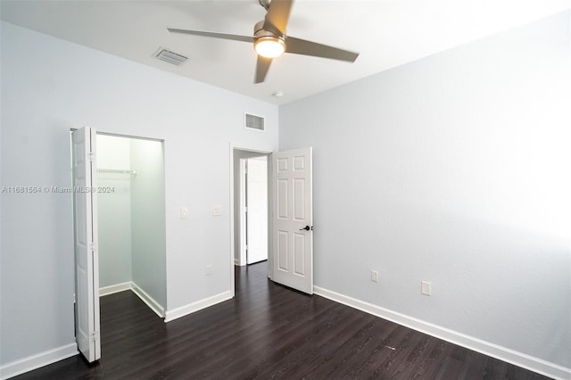 unfurnished bedroom featuring dark hardwood / wood-style flooring, a walk in closet, a closet, and ceiling fan