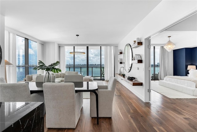 dining space featuring a water view, floor to ceiling windows, a chandelier, and dark wood-style floors