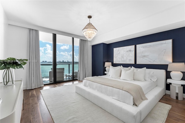 bedroom featuring an inviting chandelier, a water view, access to outside, and dark hardwood / wood-style flooring