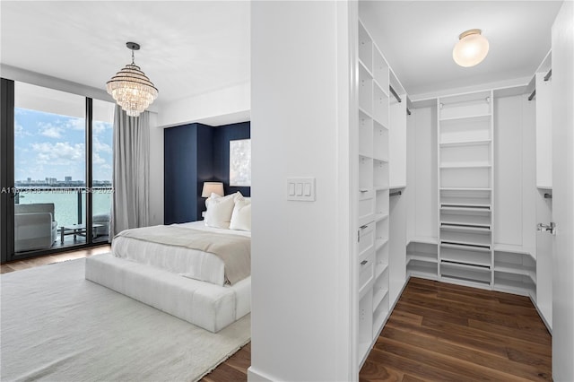 bedroom with access to outside, a chandelier, a water view, and dark hardwood / wood-style flooring