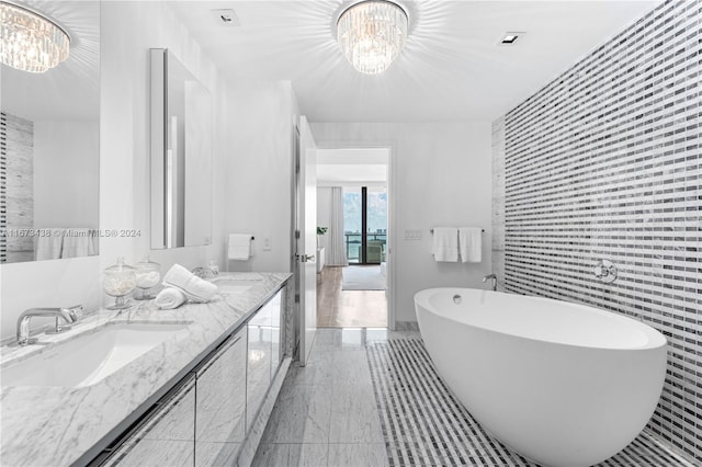 bathroom featuring a bathing tub, a notable chandelier, vanity, and tile walls