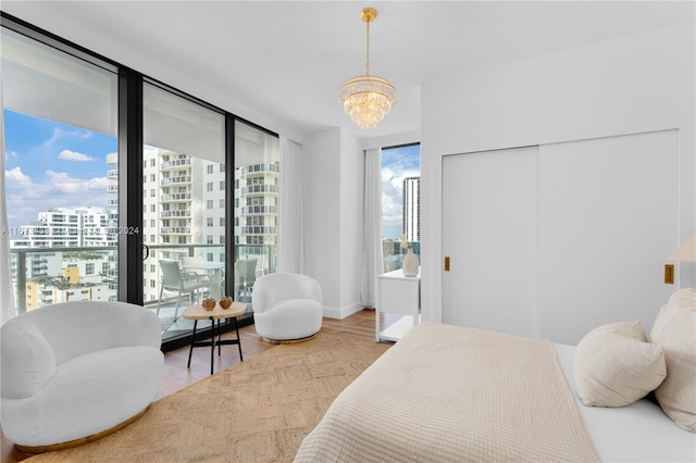 bedroom featuring baseboards, a view of city, wood finished floors, and a chandelier