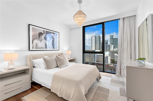 bedroom featuring expansive windows, a chandelier, and hardwood / wood-style floors