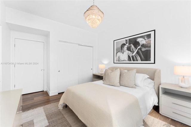 bedroom with a closet, hardwood / wood-style flooring, and a chandelier