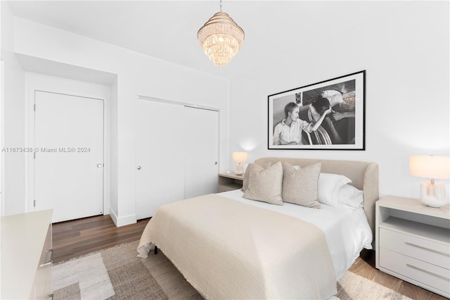 bedroom with an inviting chandelier, wood finished floors, and a closet