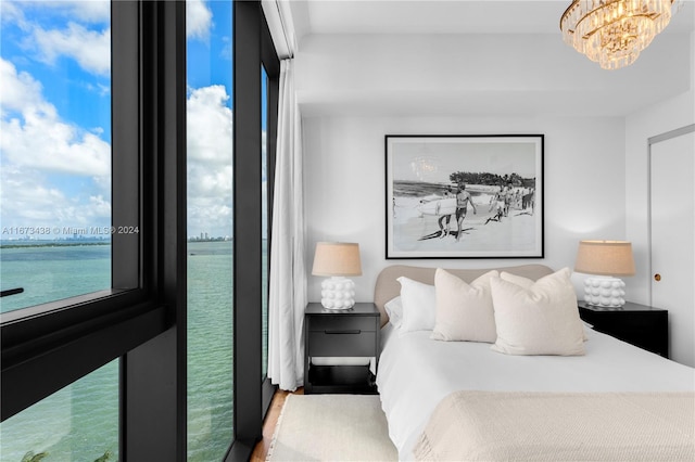 bedroom featuring a notable chandelier, wood-type flooring, and a water view