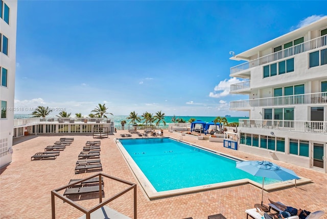 view of pool featuring a water view and a patio area