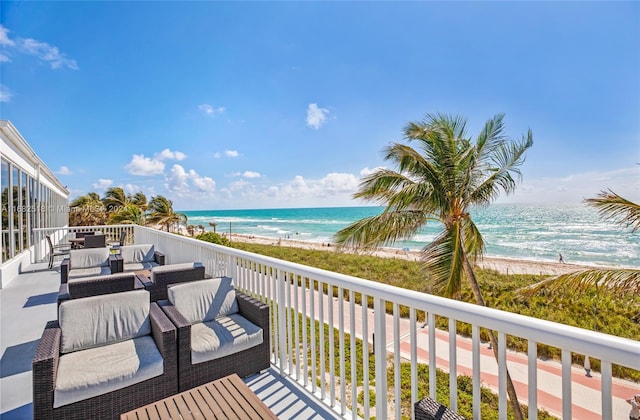 deck featuring an outdoor living space, a water view, and a beach view