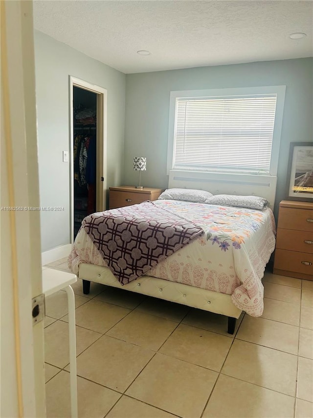 bedroom featuring a closet, a textured ceiling, a spacious closet, and tile patterned floors