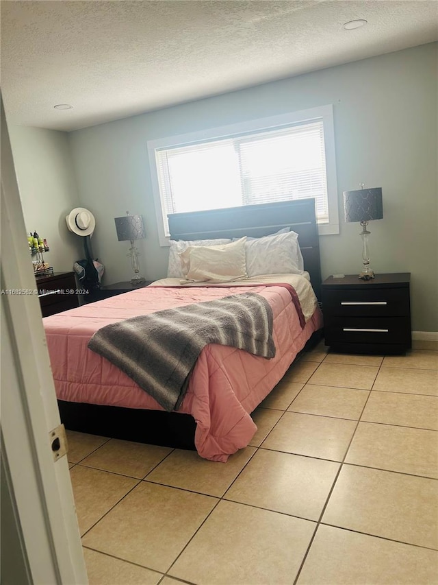 tiled bedroom featuring multiple windows and a textured ceiling