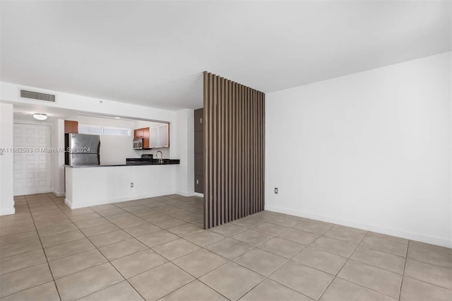 unfurnished living room featuring sink and light tile patterned flooring