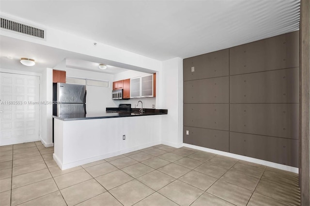 kitchen featuring sink, appliances with stainless steel finishes, light tile patterned floors, and kitchen peninsula