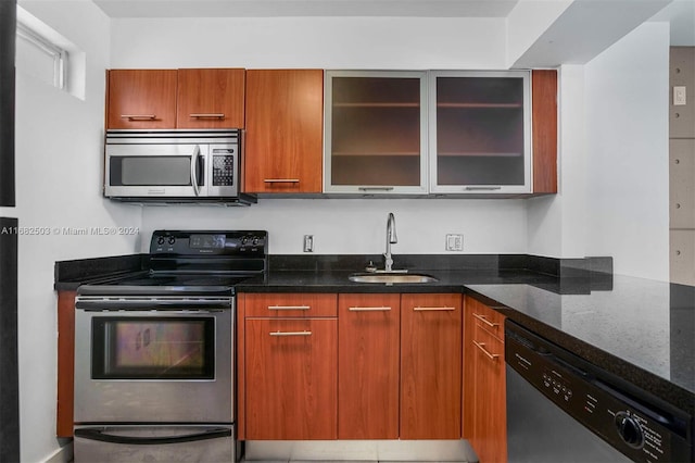 kitchen featuring stainless steel appliances, sink, and dark stone counters